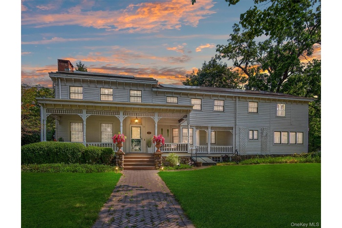 View of front facade with a porch, a chimney, a lawn, and roof mounted solar panels