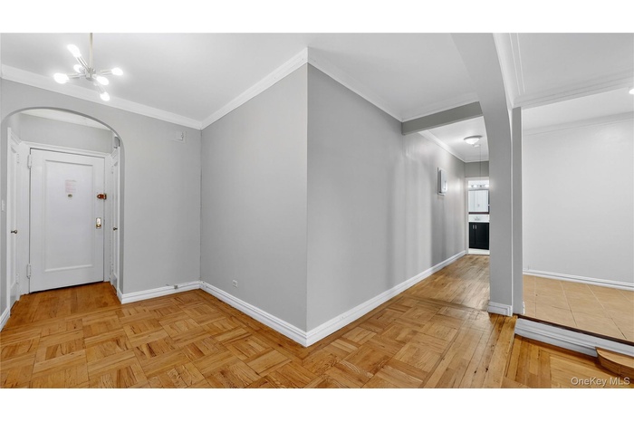 Foyer with a chandelier, crown molding, arched walkways, and parquet floors