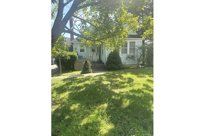 View of property hidden behind natural elements featuring a front yard