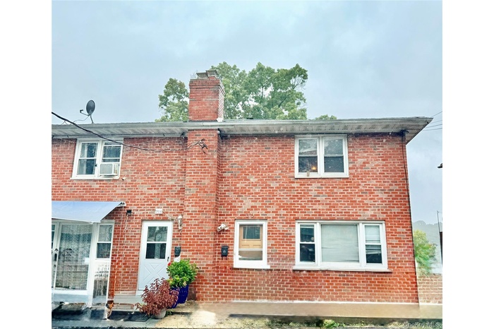 Rear view of property with brick siding and a chimney