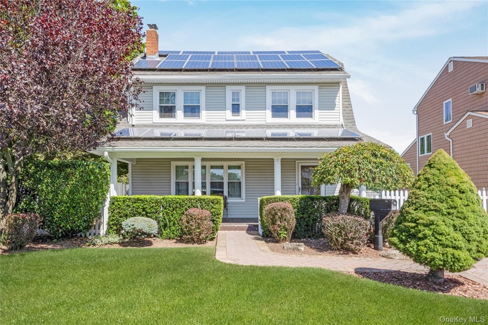View of front of property featuring a porch, and roof mounted solar panels