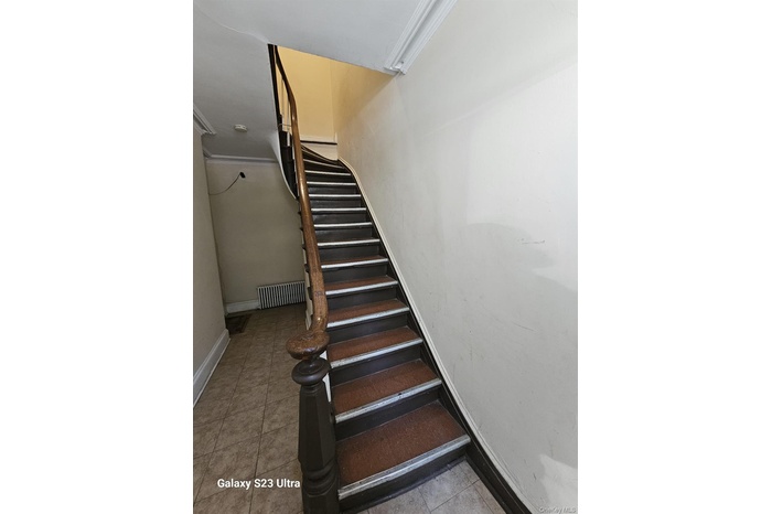 Staircase with ornamental molding and tile patterned flooring
