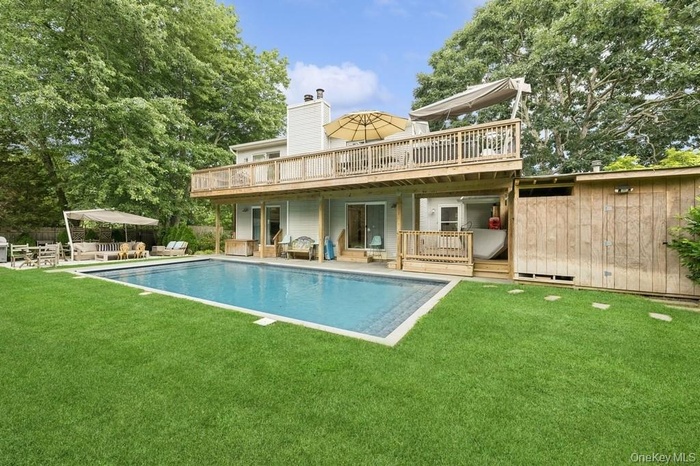 Back of house featuring a patio, a yard, a wooden deck, and a chimney