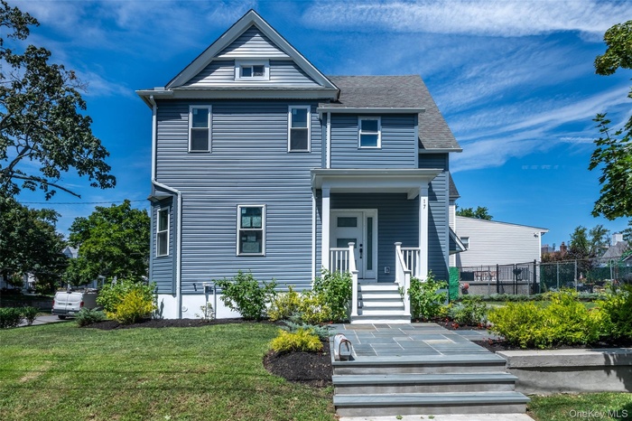 View of front of home featuring a porch, a shingled roof, and a front yard
