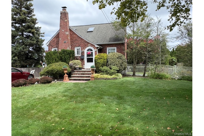 Tudor home with brick siding, a chimney, and roof with shingles