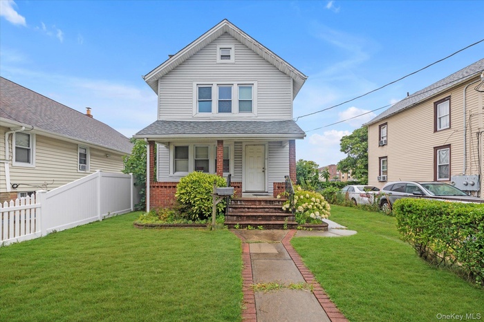 View of front of home with a porch, brick siding, and roof with shingles