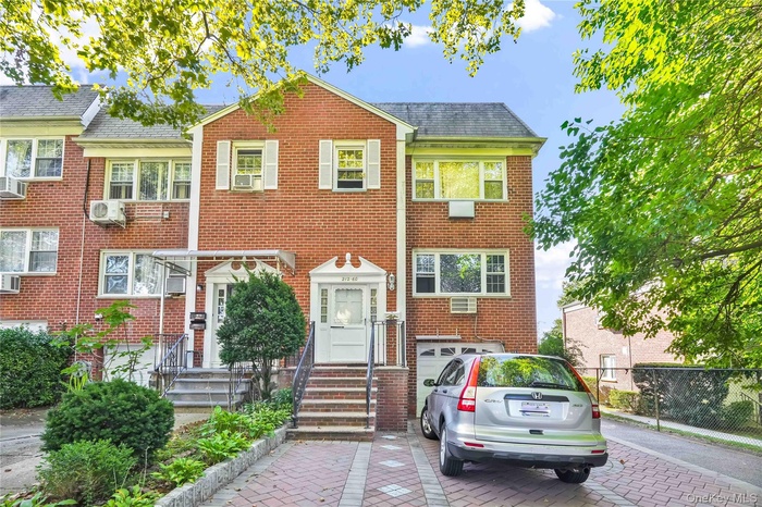 View of front facade featuring decorative driveway, a garage, and brick siding