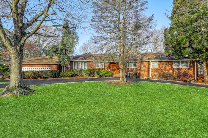 Ranch-style home featuring asphalt driveway, a front lawn, and brick siding