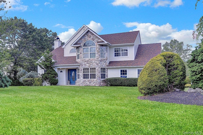 View of front of property with stone siding, a front lawn, and a shingled roof