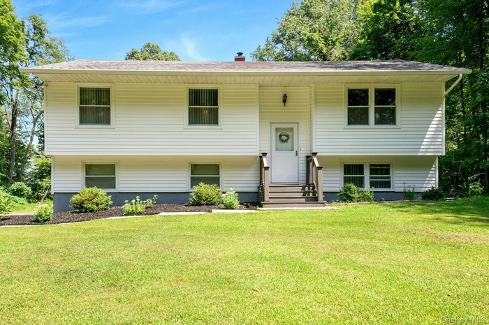 Bi-level home featuring a front yard, a chimney, and entry steps