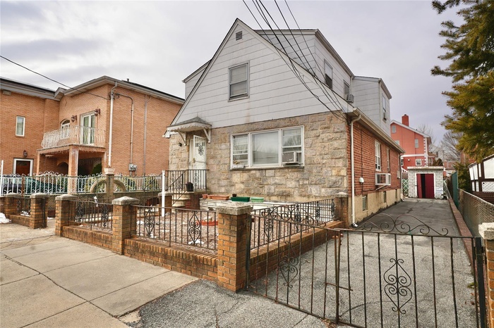 View of front of home featuring stone siding, a fenced front yard, a gate, and cooling unit