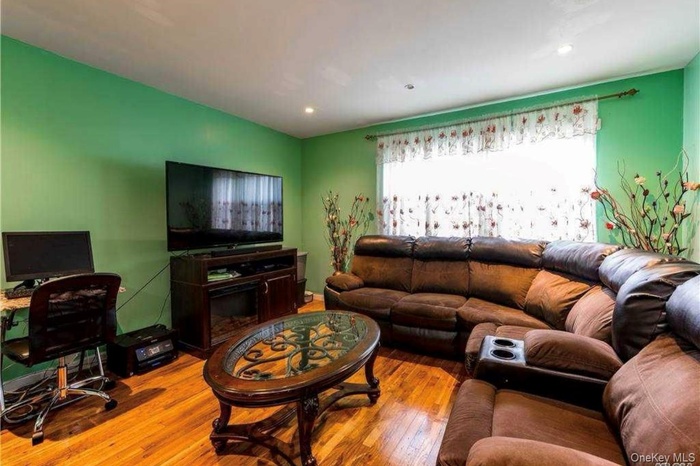 Living area featuring hardwood / wood-style flooring, vaulted ceiling, and recessed lighting