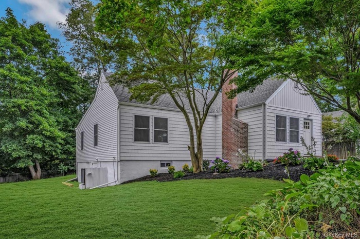 View of front of home with a shingled roof, a front lawn, and a chimney