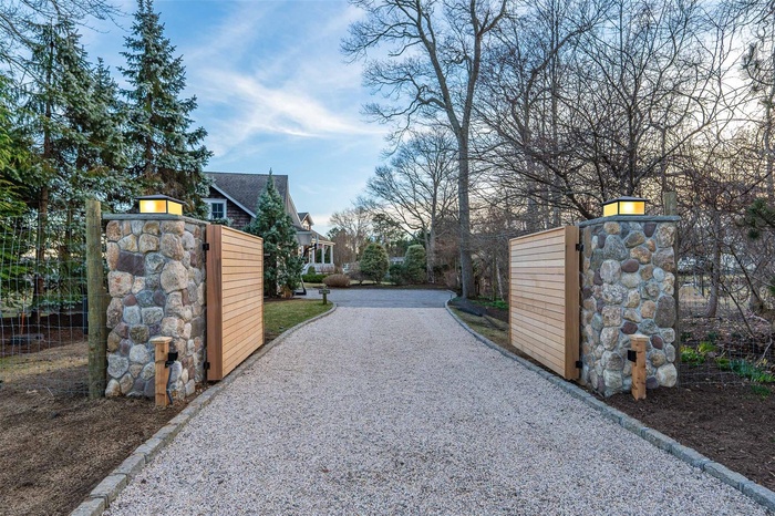 View of road with driveway, a gate, and a gated entry