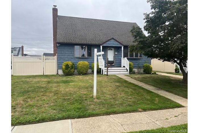 View of front of property featuring a chimney and a shingled roof