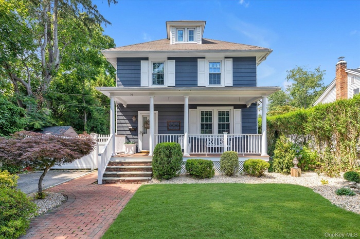 American foursquare style home featuring covered porch and a front yard