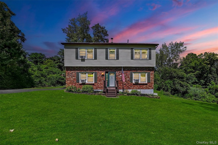 Colonial house with a yard and brick siding
