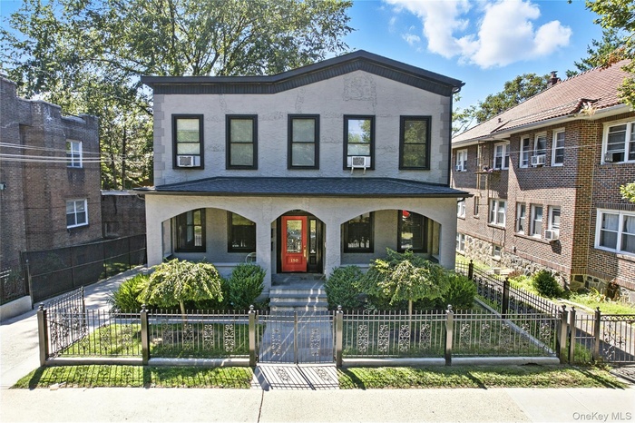 View of front facade featuring covered porch, a gate, a fenced front yard, and stucco siding