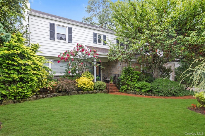 View of front of property featuring a front yard, stone siding, and covered porch