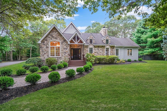 View of front of house with stone siding and a chimney