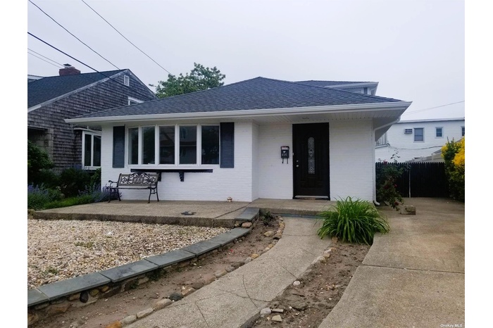 Bungalow-style home featuring a shingled roof, brick siding, and covered porch