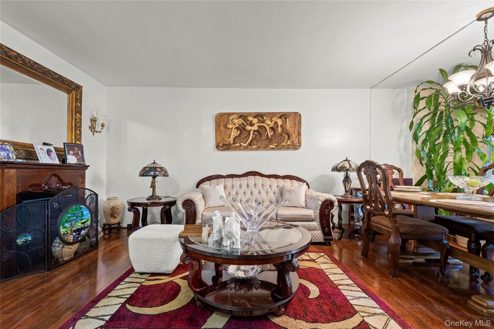 Living room featuring dark wood-style flooring and a chandelier