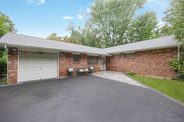 Ranch-style house with a garage, asphalt driveway, roof with shingles, and brick siding