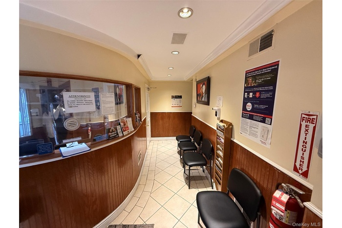 Reception with a wainscoted wall, wood walls, ornamental molding, and recessed lighting