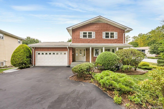 View of front of home featuring an attached garage, asphalt driveway, and covered porch