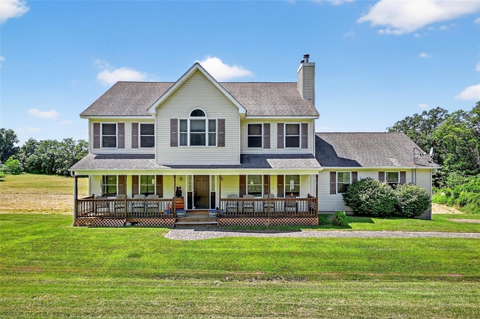 View of front of home featuring a porch, roof with shingles, a chimney, and a front lawn