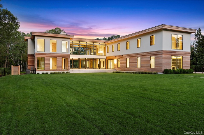 Rear view of property with a lawn and stucco siding