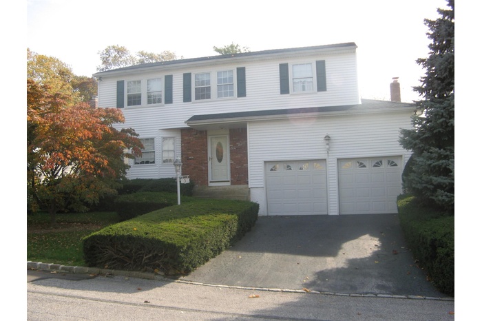 Traditional-style home featuring a garage, a chimney, and driveway