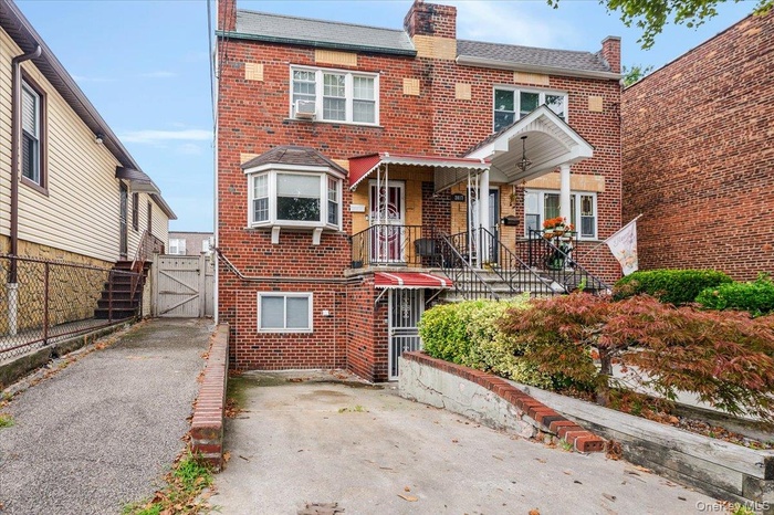 Traditional-style house featuring a gate, brick siding, a chimney, and driveway