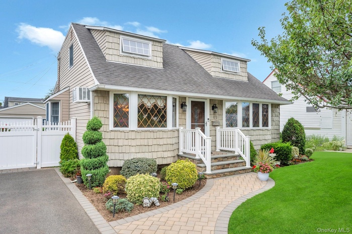 View of front of house with a shingled roof and a front yard