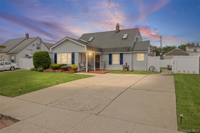 View of front of home featuring driveway, a shingled roof, a chimney, and a gate
