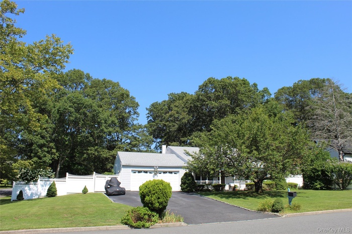 View of front facade featuring an attached garage, a chimney, and driveway
