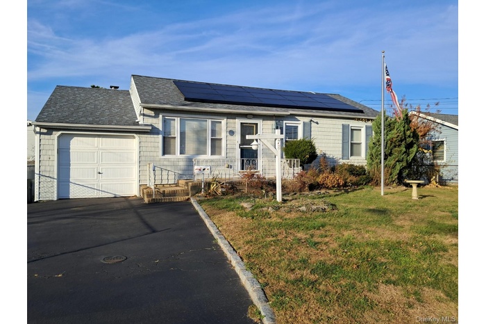 Ranch-style home featuring an attached garage, roof with shingles, a front lawn, and driveway