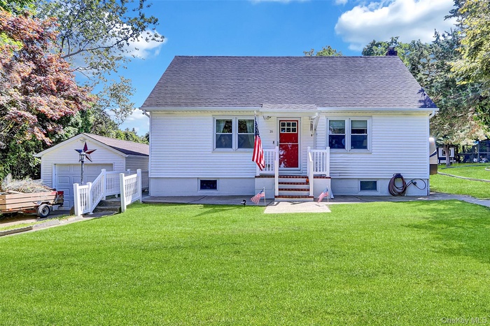 View of front of property featuring a a front yard, and a garage (detached)