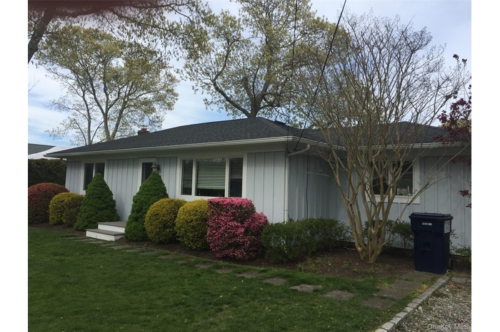 View of front of house featuring a front yard, board and batten siding, a shingled roof, and a chimney