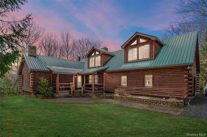 Front of the home at dusk with covered porch, and the lawn