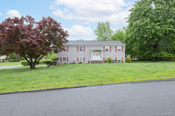 Bi-level home with a front lawn and entry steps
