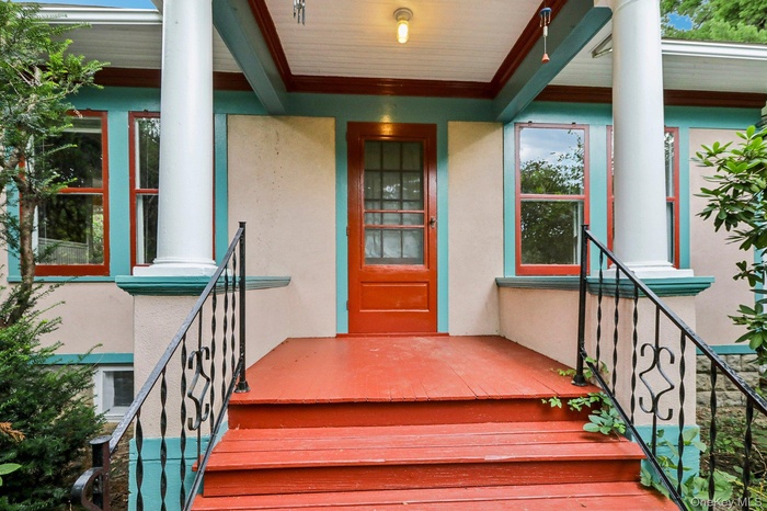 Property entrance with covered porch and stucco siding