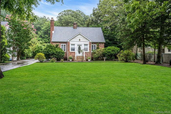 View of front of property featuring roof with shingles, a chimney, and brick siding