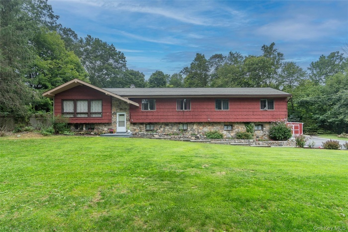 Front face of home with a front yard and stone siding