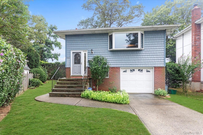 Bi-level home with a garage, driveway, and brick siding