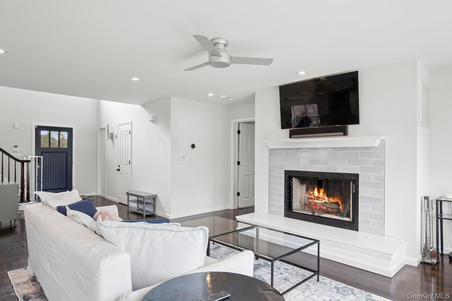 Living area featuring recessed lighting, stairway, a brick fireplace, ceiling fan, and wood finished floors