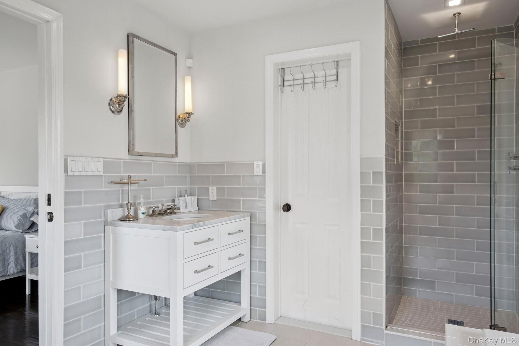 Full bath with a shower stall, vanity, tile walls, and wainscoting