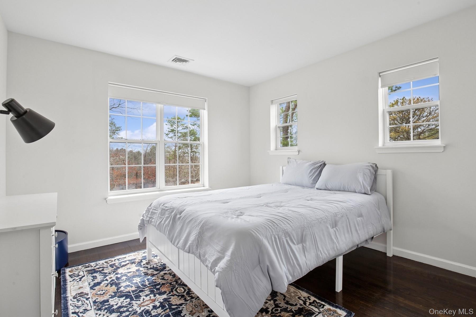 Bedroom with visible vents, dark wood-style flooring, and baseboards