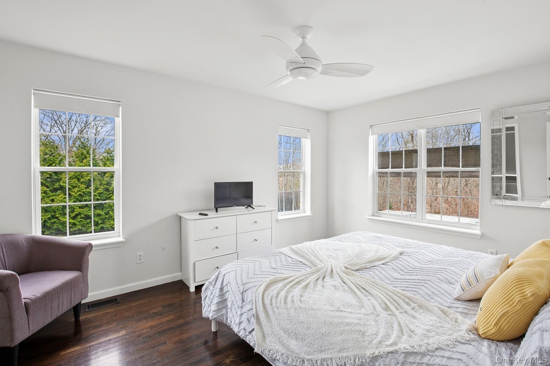 Bedroom featuring dark wood-type flooring, visible vents, baseboards, and a ceiling fan