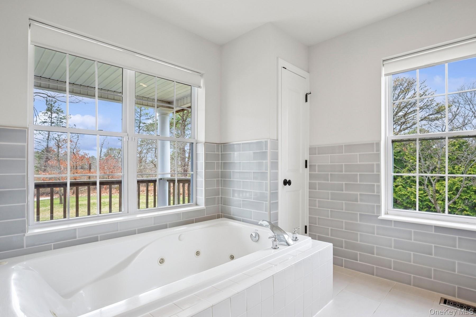 Bathroom with visible vents, tile walls, a whirlpool tub, and tile patterned flooring